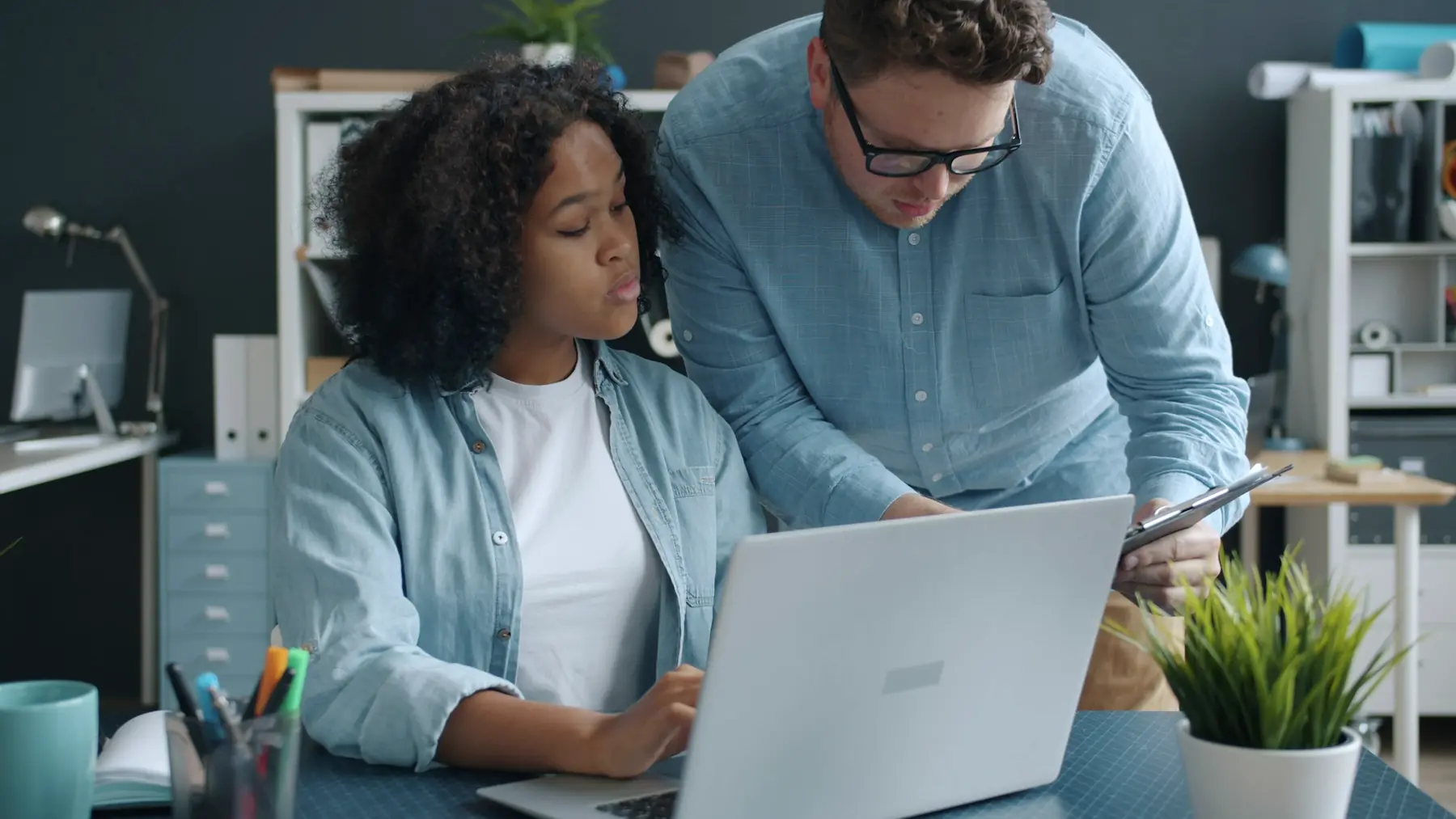 An experienced colleague guiding a younger teammate through work on a laptop