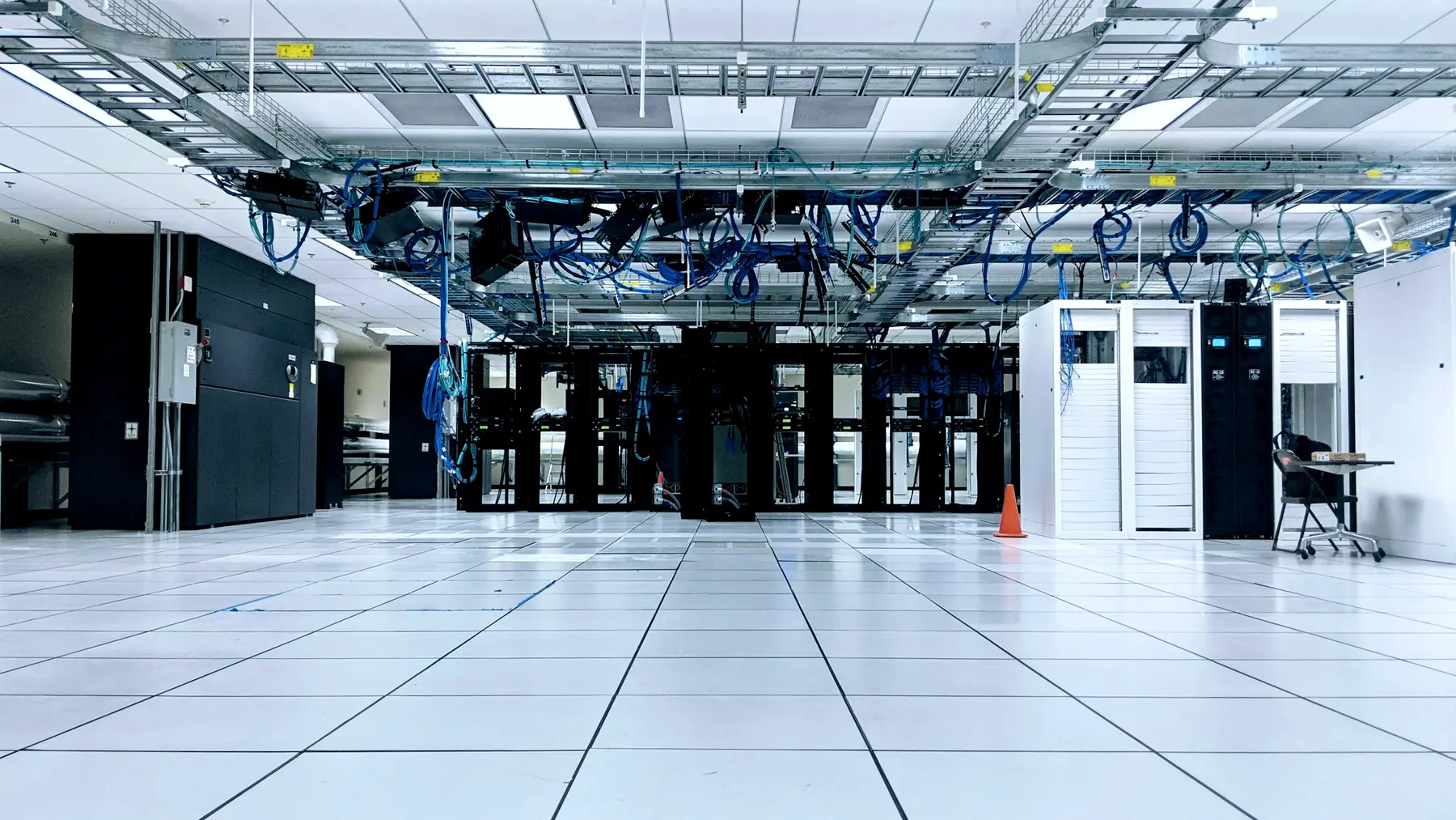 A data centre hall with rows of server racks under overhead cable trays