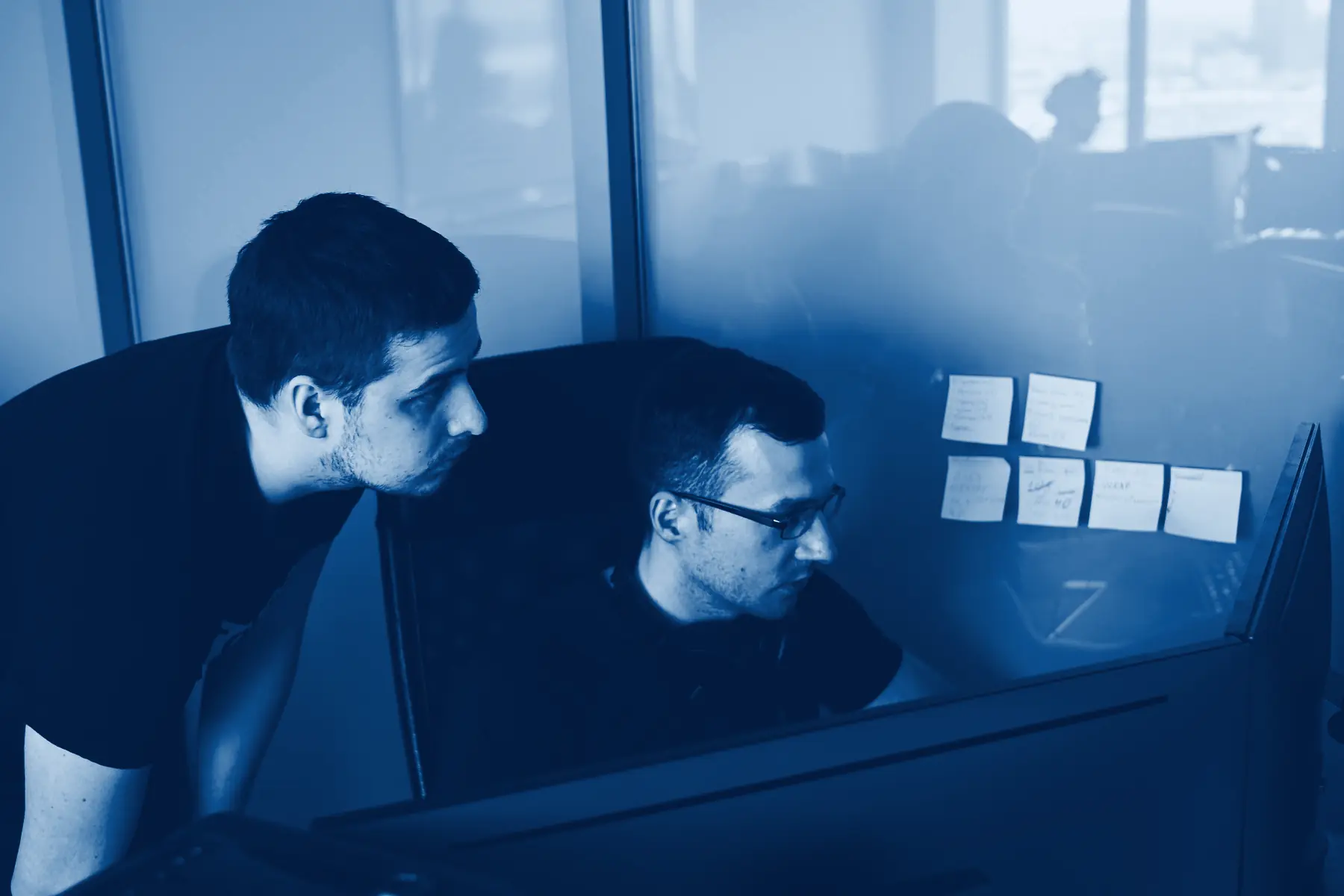 Two developers working through code together at one monitor