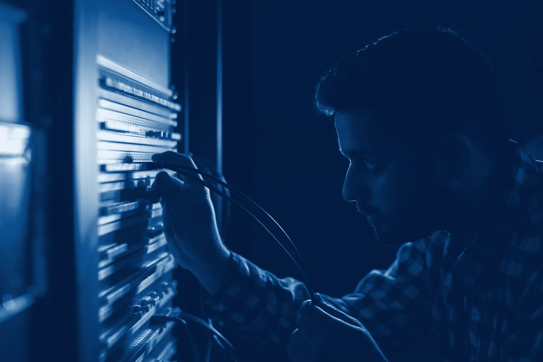 An engineer working the cabling at a server rack