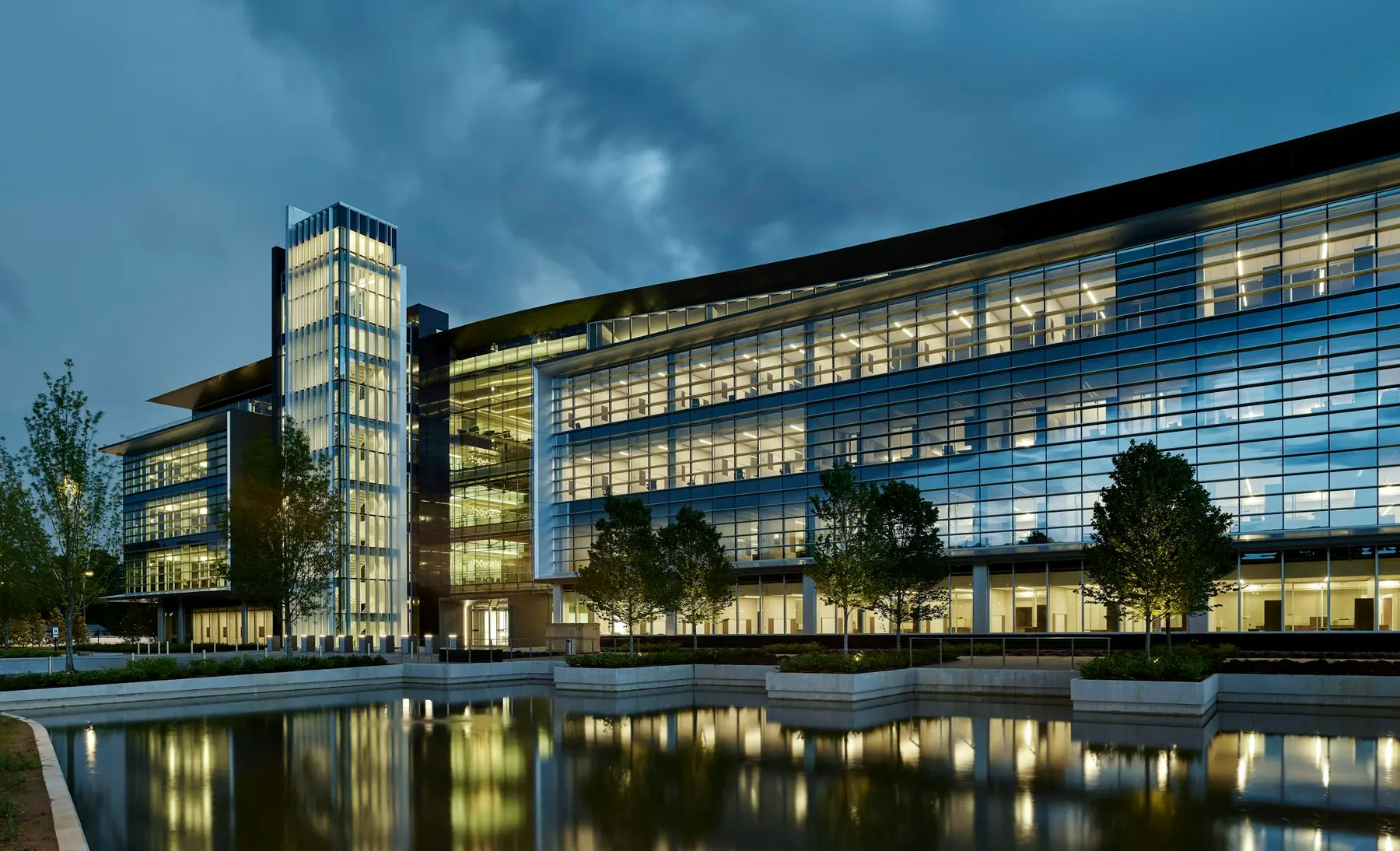 A glass office building lit up at dusk