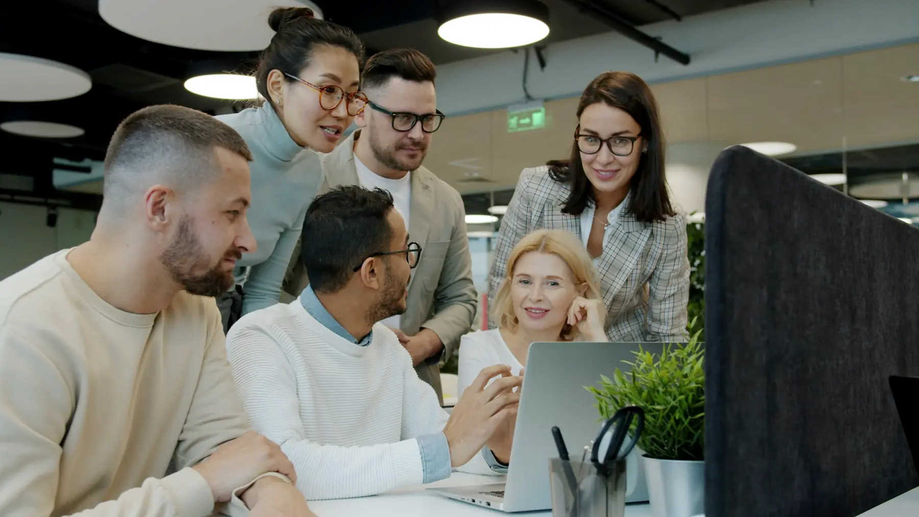Colleagues gathered around a laptop, working through a plan together