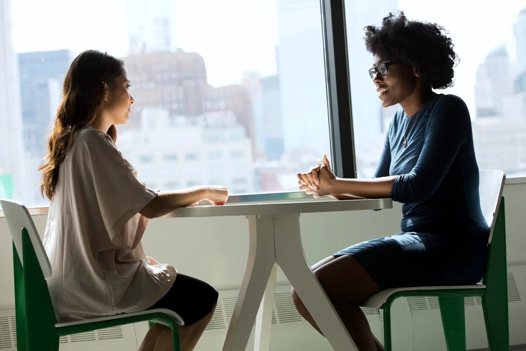 A one-to-one interview at a table by a bright office window