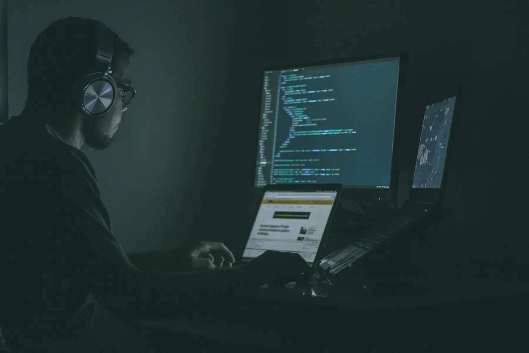 An engineer at a bank of monitors in a dark room